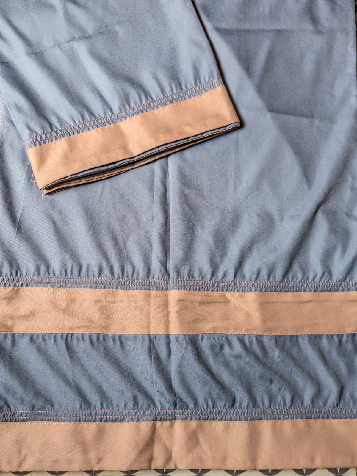 Deep teal satin fabric with gold scalloped embroidery along the hem
