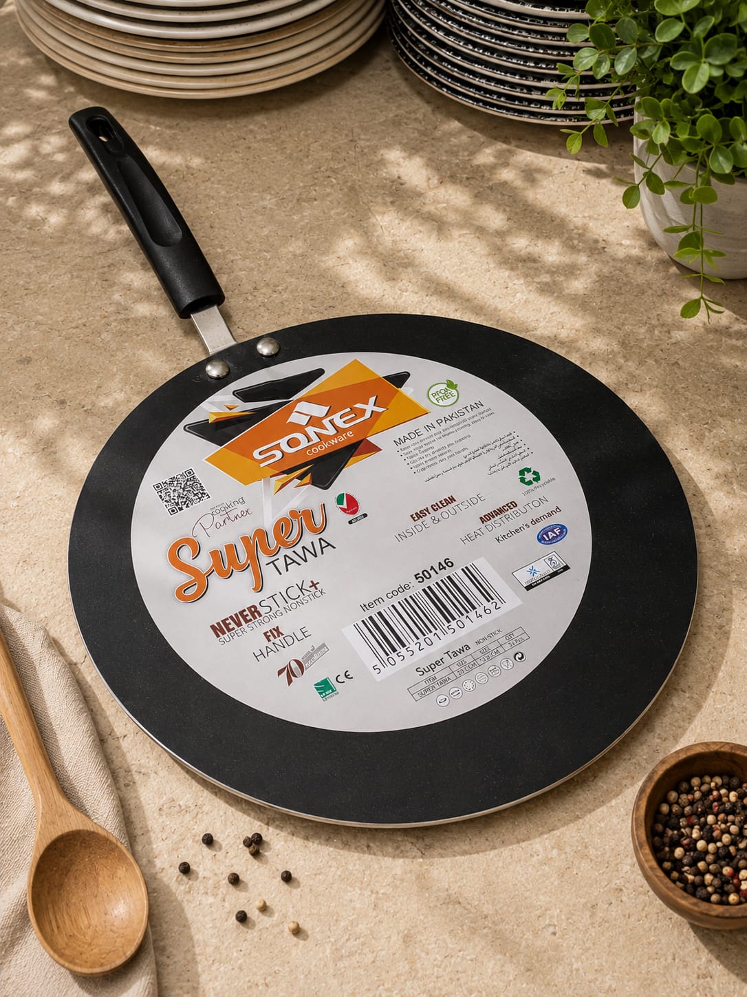 Sonex Super Tawa non-stick griddle photographed on a stone surface with stacked plates and peppercorns